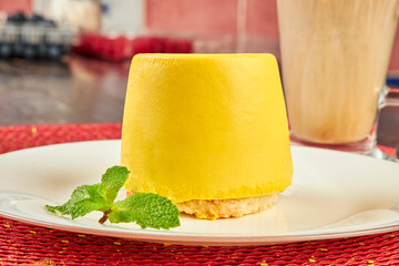 Yellow mini cake covered with yellow glaze on table in cafe close up