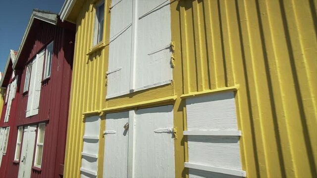 Old fishing village wooden seafront shack boutiques. row of brightly colored buildings in Sweden Smogen pier. Moving slow motion shot at houses. Red yellow Swedish buildings with white window frames