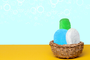 Basket with three colorful terry towels or cosmetic for body care on a yellow table over blue background with copy space. For your product display montage.