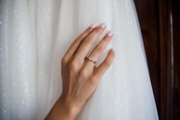 hand of bride with ring on wedding dress