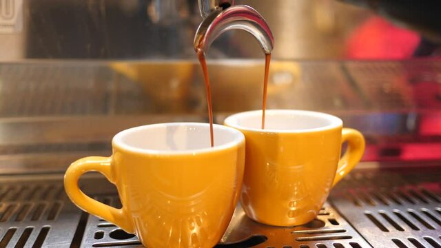 Making pouring coffee to go on expresso machine in cafe bar in small cups yellow colors