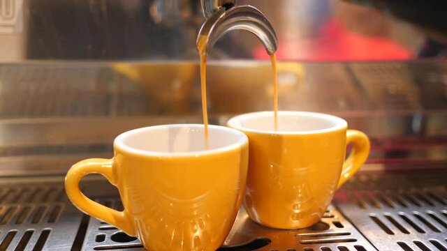 Making pouring coffee to go on expresso machine in cafe bar in small cups yellow colors