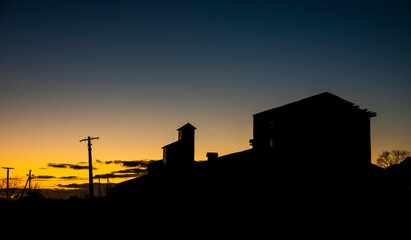 Obraz premium Agricultural buildings on the background of sunset