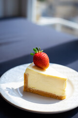 Slice of delicious strawberry cheesecake on white plate with fresh strawberries, close-up.