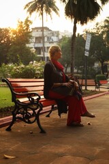 A girl sits in a Park in the city of Panaji at sunset. State Of Goa. India. November 2020