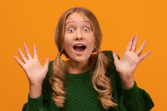 Image of shocked blonde teen expressing surprise on camera. Studio shot, yellow background. Human emotions concept