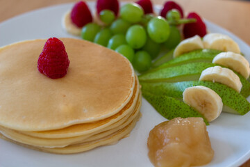 Pancakes mit Obst und Nutella oder Sternen auf einem Teller angerichtet Bunt