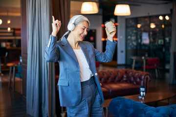 Cheerful woman with coffee listening to music in cafe