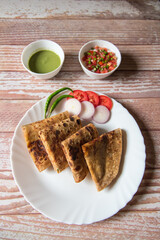 Vertical view of Indian dish alu paratha in a plate along with condiments