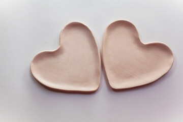 Obraz premium Two heart plates made of fireclay on a white background. Creation of ceramics. Bisquit firing ceramics.