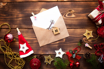 Christmas flat lay on a wooden background with keys to new house in the center with a envelope with a note sheet. New year, transfer, shares of the mortgage, the rental of a cottage. Space for text