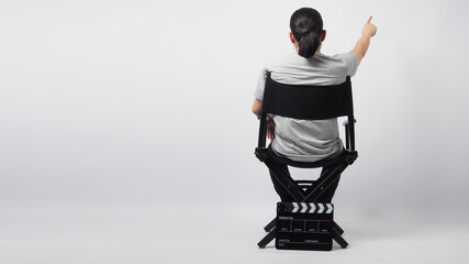 A man is sitting on director chair and hand's is pointing with clapper board put on the ground.It...