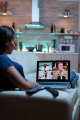 Woman freelancer having web chat conference sitting on sofa in living room. Remote worker discussing at online meeting, consulting with colleagues using videocall and webcam working in front of laptop