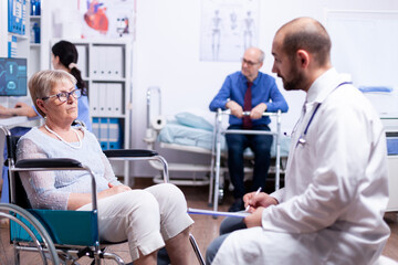Obraz premium Doctor consultation in recovery clinic of handicapped senior woman in wheelchair. Man with disabilities ,walking frame sitting in hospital bed. Health care system, patients.