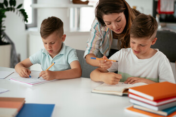 Fototapeta premium Mother helping her son with homework at home. Little boy learning at home..
