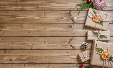 Wrapping Christmas gift, close up. Unprepared presents on wooden background with orange, cinnamon, ribbon, scissors, spruce branch, decor elements and items, side view. New year DIY packing Concept.