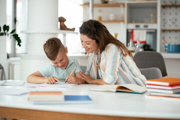 Mother helping her son with homework at home. Little boy learning at home..