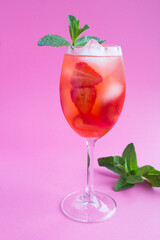Drink with strawberries and ice in a glass on the pink  background
