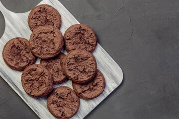 Homemade Baking Desserts Sweet Food, Brownie Round Dark Brown Chocolate Coffee Cookies with fresh Cocoa on a cutting board on a black Background on a Table
