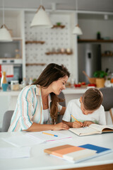 Mother helping her son with homework at home. Little boy learning at home..