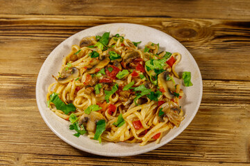 Pasta with mushrooms and tomato sauce on wooden table