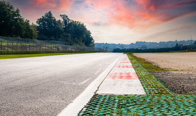 Straight asphalt track diminishing perspective motorsport circuit empty red sunrise sky background