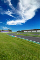 Hairpin bend and turn exit with curb and green field on motor sport circuit asphalt track