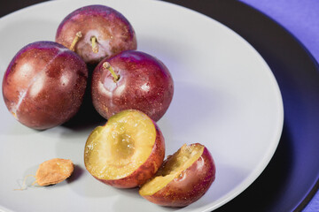 Plums on a white and black plate