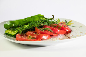 Tomatoes, cucumbers, fennel and burning green pepper on a white plate with a pattern