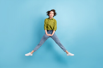 Photo portrait of surprised woman jumping up spread legs isolated on pastel light blue colored background