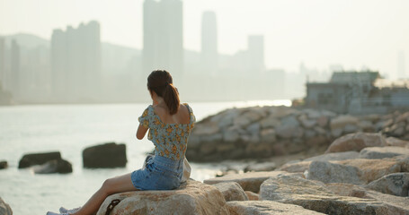 Woman plays with camera and sits beside the sea