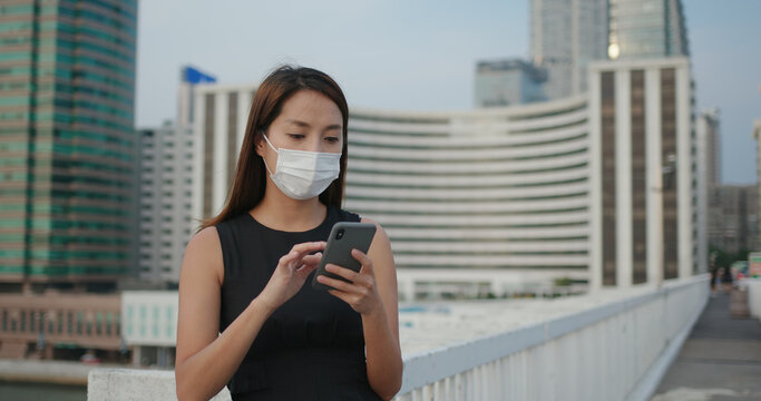 Woman wear face mask and use of mobile phone in city © leungchopan
