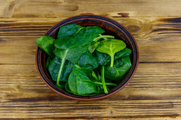 Fresh green spinach leaves in bowl on a wooden table