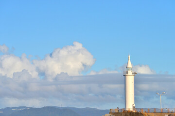 江の島の白い灯台のある防波堤の景色