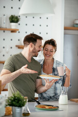  Husband and wife making pancakes at home. Loving couple having fun while cooking.