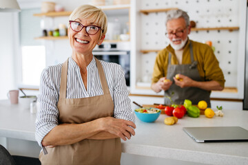 Senior couple having fun in kitchen with healthy food at home