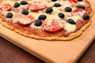 homemade pizza, vegetarian food, baked vegetables and cheese, tomatoes and olives, delicious food on a wooden background