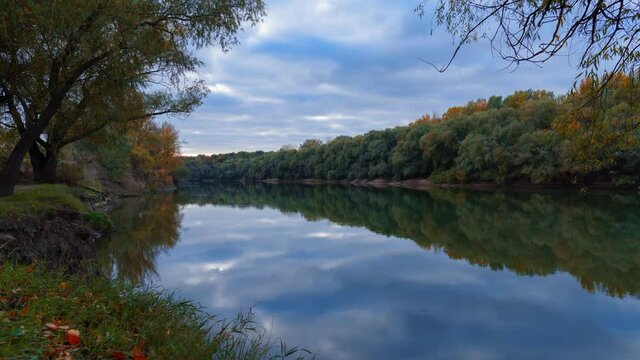 autumn landscape, beautiful sunset and bright colorful forest in the evening, trees near river and blue sky, day to night tme lapse