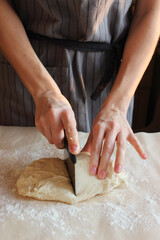 Household. A woman's hands cut the dough for baking. Family celebration.