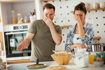  Husband and wife making pancakes at home. Loving couple having fun while cooking.