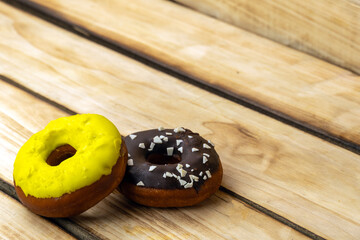 Two donuts yellow and chocolate on a wooden background. Free space for text. World donut da