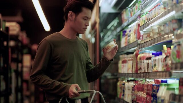Asian man doing grocery shopping at a supermarket