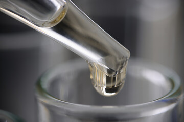 Drop of clear liquid drips into test tube on measuring tube. The benefits of water in every drop concept