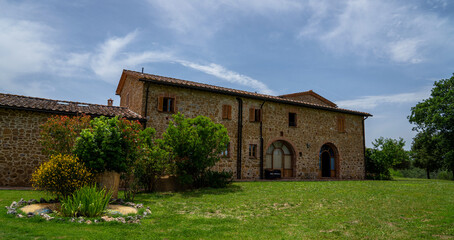Fototapeta na wymiar A beautiful hilltop manor house surrounded by fields and vineyards in Tuscany. Picturesque old cozy house with a tiled roof. The winery. Eco tourism. Countryside farm. Italy, Europe.