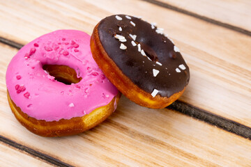 Two raspberry and chocolate donuts on a wooden background. Free space for text. World donut day