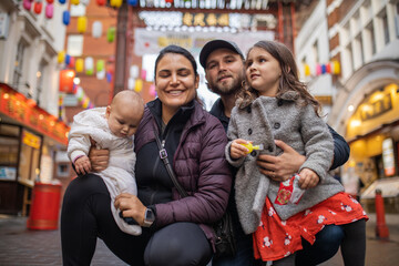 Two happy parents and their two daughters posing in a blurry Chinatown alley