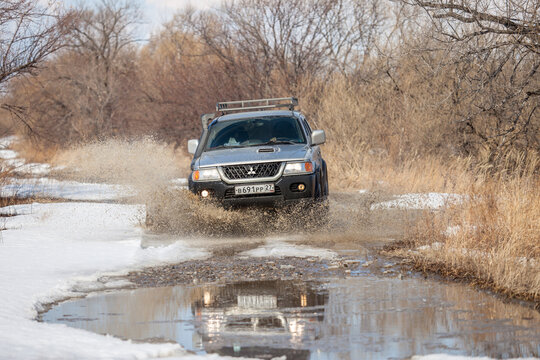 KHABAROVSK, RUSSIA - MARCH 25, 2017: Mitsubishi Pajero Sport on dirt road in early spring making splashes from a puddle