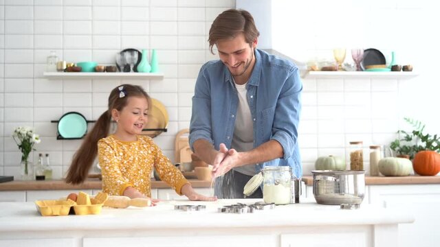 Happy dad and daughter play with flour, cooking together, laughing, having fun in modern kitchen
