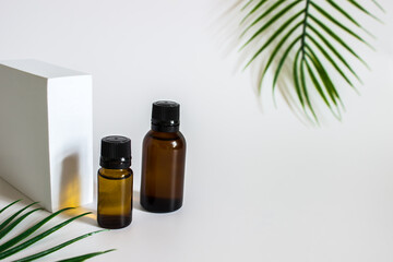 glass brown jars with plant stracts and oils on a light white background. For cosmetics or cosmetology background. stand for advertising beauty products. Plants decor eucalyptus, fern, spruce