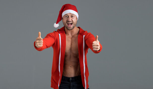 Muscular Strong Man Dressed As Santa Claus Shows Thumb Up. New Year Is A New You, Fitness Concept.